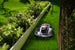 Sunseeker X7 Gen2 robot lawn mower mowing beside garden greenery