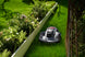 Sunseeker X7 Gen2 robot lawn mower mowing beside garden greenery