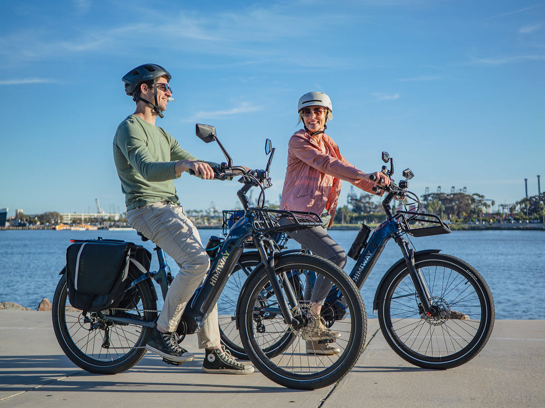 Two riders on Himiway A7 e-bikes along a waterfront path