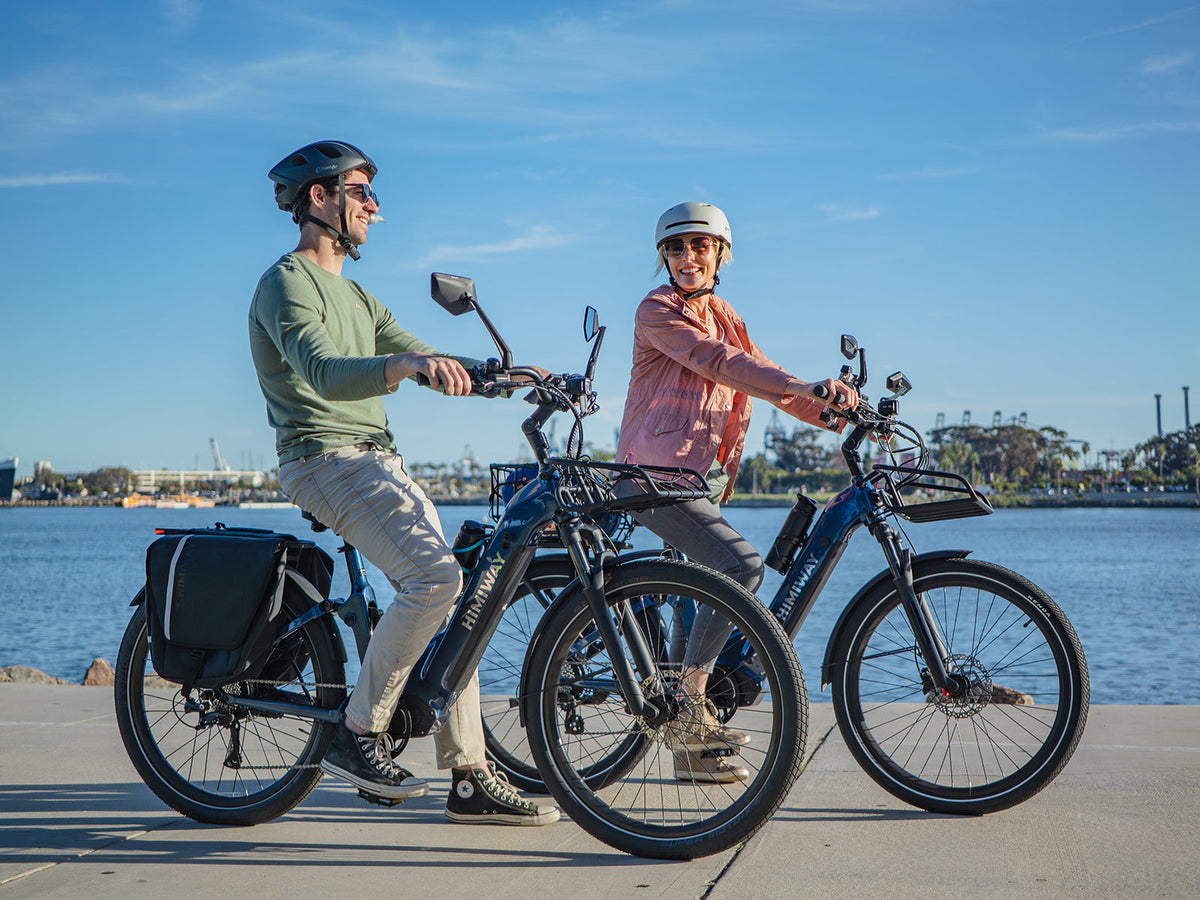 Two riders on Himiway A7 e-bikes along a waterfront path