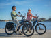 Two riders on Himiway A7 e-bikes along a waterfront path